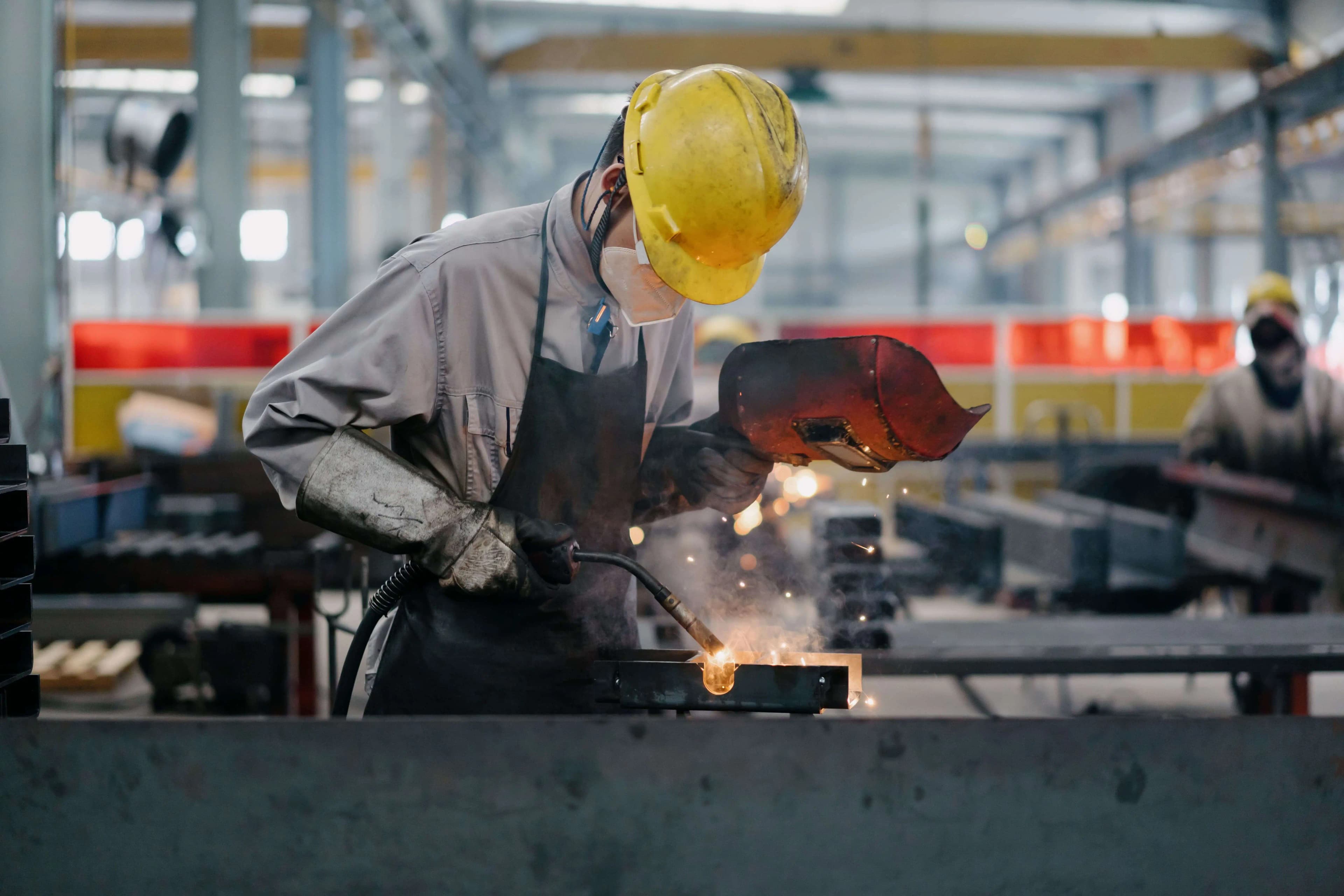 Spawacz pracujący przy obróbce metalu w zakładzie przemysłowym